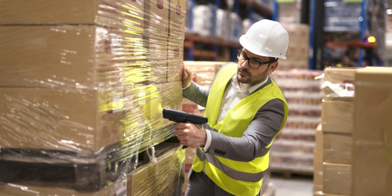 Male warehouse worker using bar code scanner to analyze newly arrived goods for further placement in storage department. Male warehouse worker using bar code scanner to analyze newly arrived goods for further placement in storage department.
