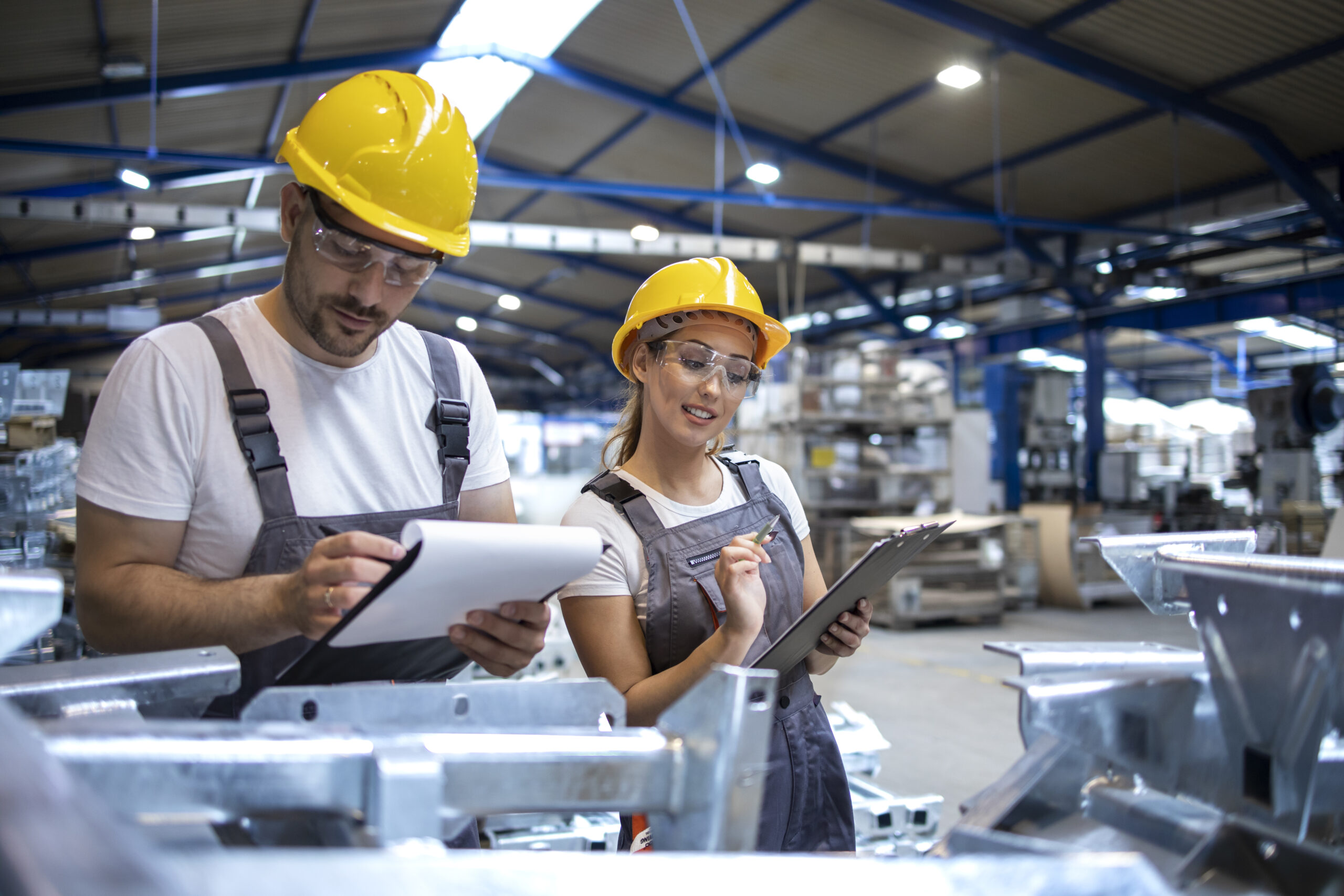 Factory workers checking quality of products in large industrial hall.