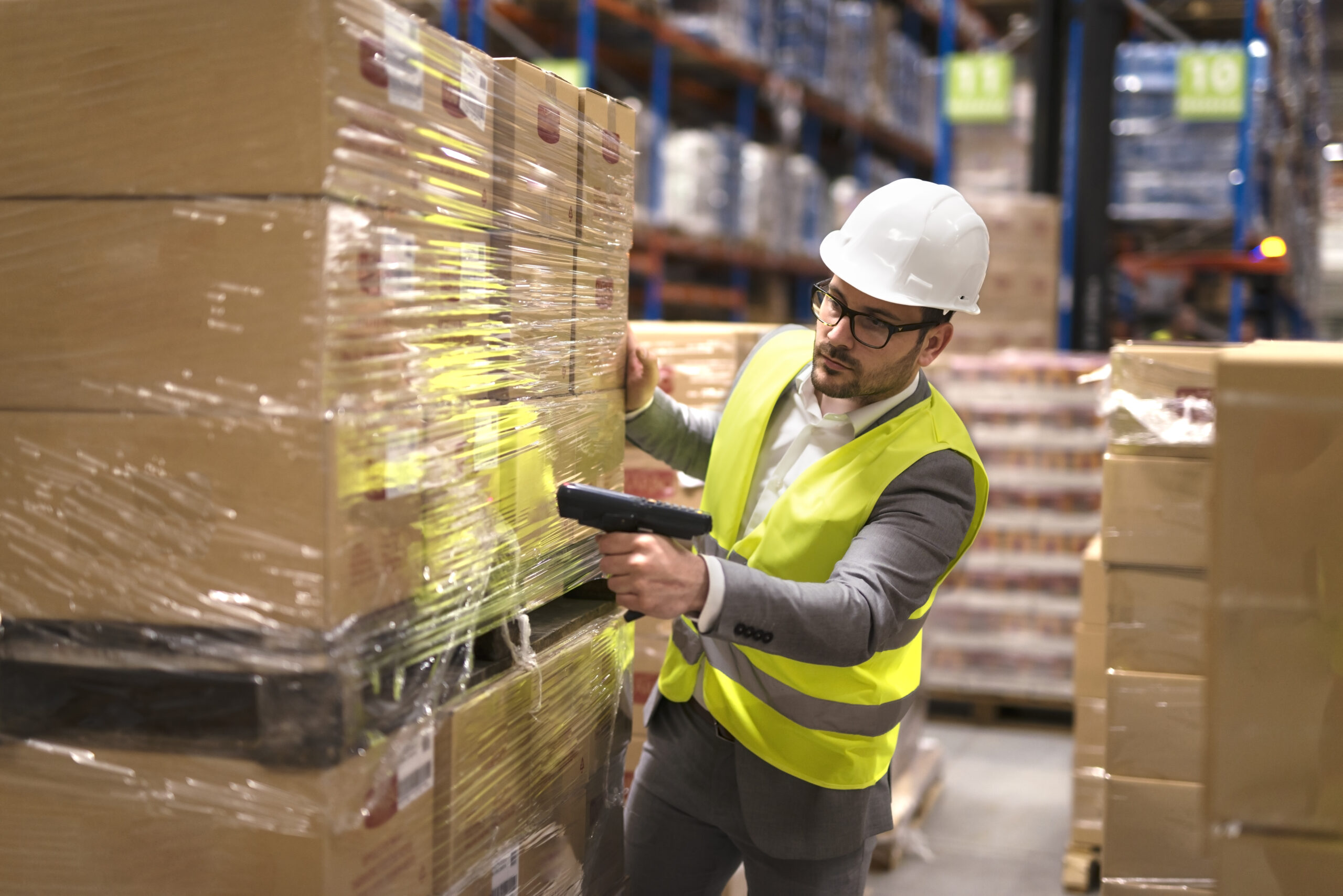 Male warehouse worker using bar code scanner to analyze newly arrived goods for further placement in storage department.